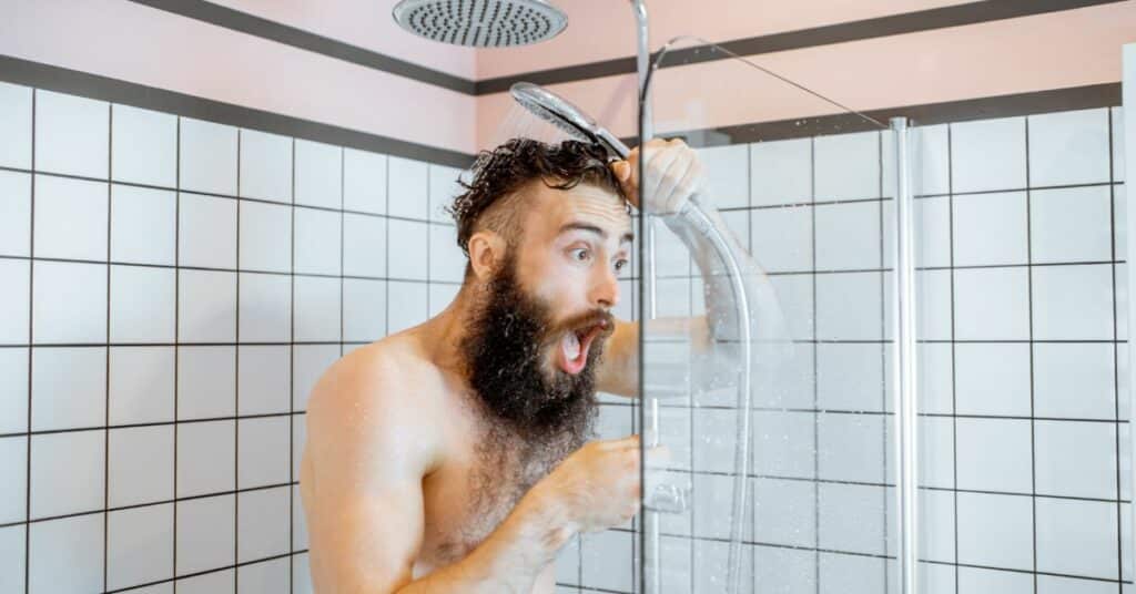 Man having a cold shower due to no hot water
