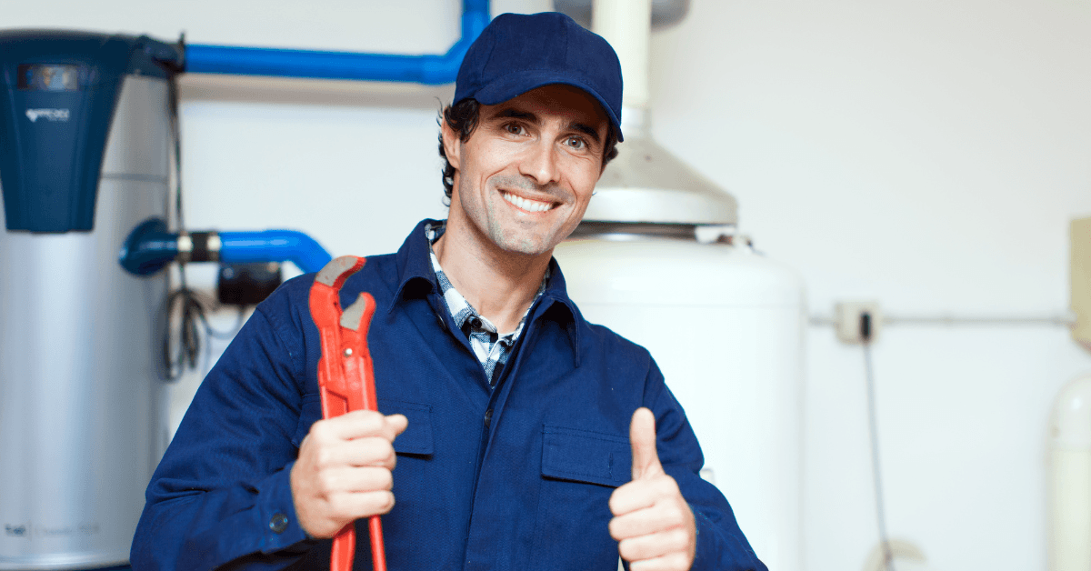 A reliable plumber holding a tool while smiling and giving a thumbs up