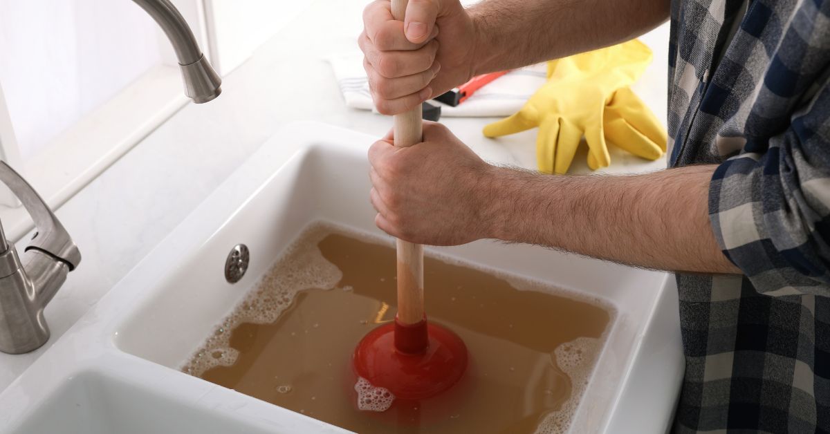 Person plunging a blocked drain due to sewer blockage